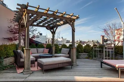 a wooden pergola with couches and a bench on a patio at Roedonis SoHo in New York