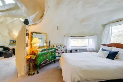 a bedroom with a large bed and a mirror at Less Than 6 Mi to Arlington Whimsical Stone Abode! in Sandgate