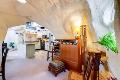 a kitchen and living room in a home with a log wall at Less Than 6 Mi to Arlington Whimsical Stone Abode! in Sandgate
