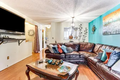 a living room with a brown leather couch and a table at 3 Mi to Dtwn New Haven Colorful Condo with Yard! in West Haven