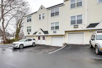a white car parked in a parking lot in front of a house at 3 Mi to Dtwn New Haven Colorful Condo with Yard! in West Haven