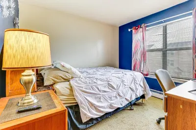 a bedroom with a bed and a desk with a lamp at 3 Mi to Dtwn New Haven Colorful Condo with Yard! in West Haven
