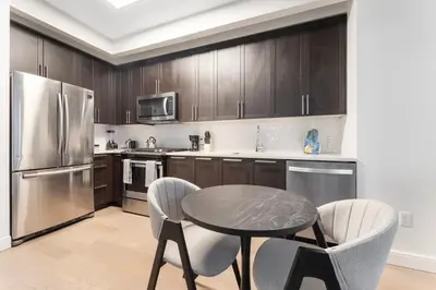 a kitchen with a table and two chairs and a refrigerator at Queens Studio Jewel Luxury and Comfort Combined in Mary Immaculate Hospital Heliport