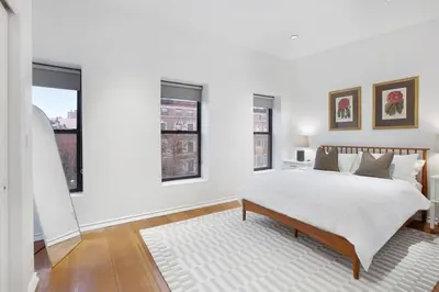 a white bedroom with a bed and two windows at Luxury Oasis in Manhattan in New York