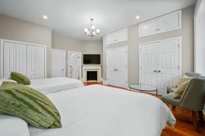 a bedroom with two beds and a chair and a fireplace at Luxury Townhouse in NYC in New York