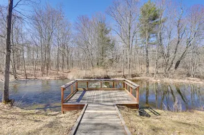 a wooden bridge over a pond in a forest at Close to Trails Studio with Water Views in Wurtsboro