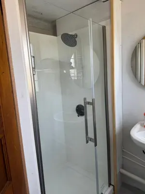a glass shower in a bathroom with a sink at Tiny house of Walnut Grove in Ashland