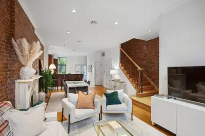 a living room with white furniture and a brick wall at Luxury Oasis in Manhattan in New York