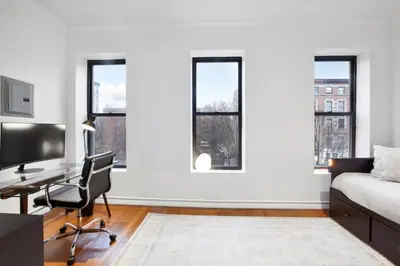 a living room with a bed desk and windows at Luxury Oasis in Manhattan in New York