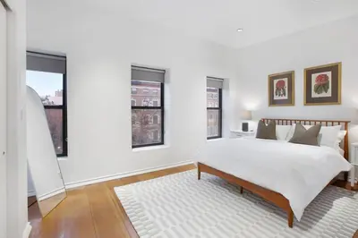 a white bedroom with a bed and two windows at Luxury Oasis in Manhattan in New York