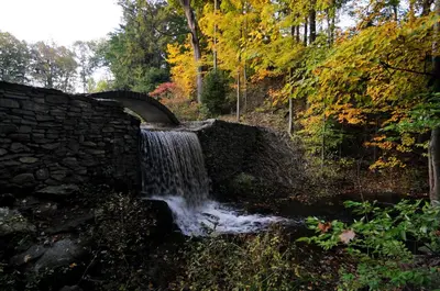 a stone bridge over a stream with a waterfall at Butter Milk Falls Inn and Spa in Milton
