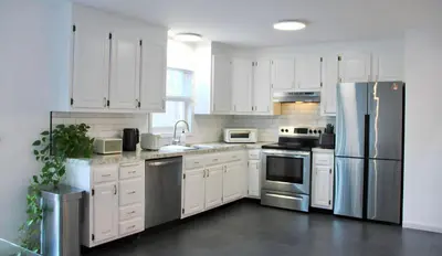 a kitchen with white cabinets and stainless steel appliances at Country House in Waterbury