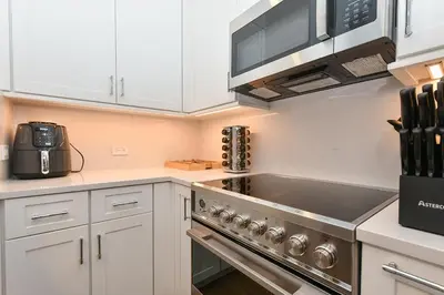 a kitchen with white cabinets and a stove top oven at Sophisticated 3 Bedroom Duplex in the Heart of Midtown in New York