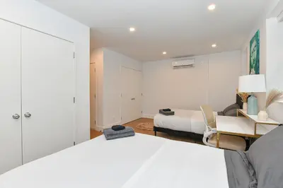 a white bedroom with a bed and a desk at Sophisticated 3 Bedroom Duplex in the Heart of Midtown in New York