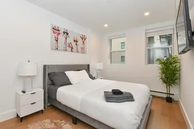 a white bedroom with a bed and two windows at Sophisticated 3 Bedroom Duplex in the Heart of Midtown in New York