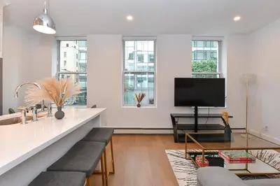 a living room with a table and a tv at Sophisticated 3 Bedroom Duplex in the Heart of Midtown in New York