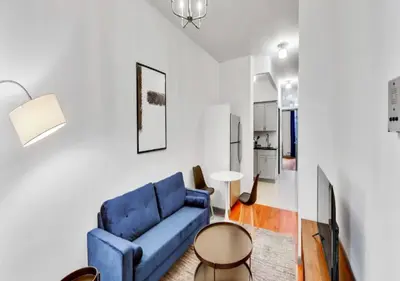 a living room with a blue couch and a table at Charming 3BR Apartment in NYC in New York