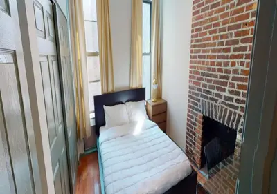a bedroom with a bed next to a brick fireplace at Charming 3BR Apartment in NYC in New York