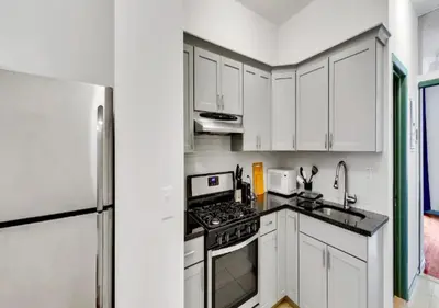 a white kitchen with a stove and a refrigerator at Charming 3BR Apartment in NYC in New York