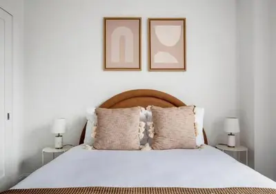 a bedroom with a white bed with two pictures on the wall at 3BR Furnished Loft in Midtown West in New York