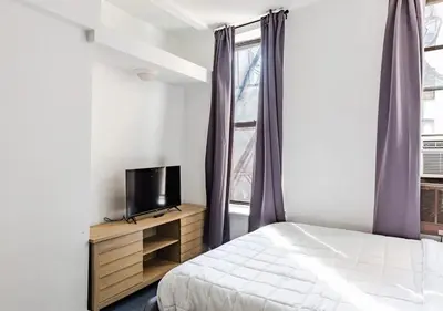 a bedroom with a bed and a tv and a window at Cozy Studio! Steps to Central Park & Upper E Side!, June To Aug 90 Days Stay Required in New York
