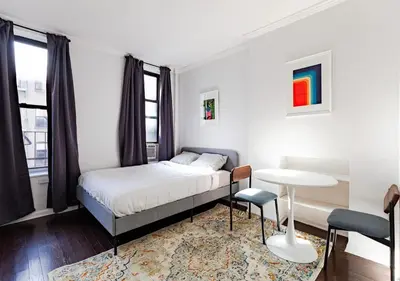 a small bedroom with a bed and a table at Spacious Upper East Side Studio, June To Aug 90 Days Stay Required in New York