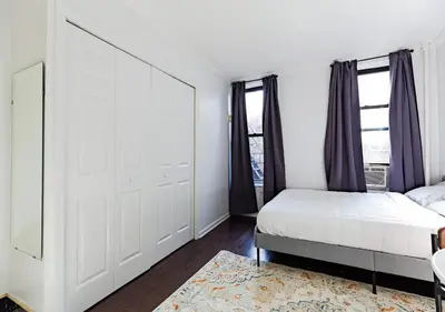 a bedroom with a bed and a large window at Spacious Upper East Side Studio, June To Aug 90 Days Stay Required in New York