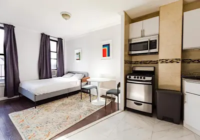 a small bedroom with a bed and a kitchen at Spacious Upper East Side Studio, June To Aug 90 Days Stay Required in New York