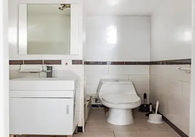 a white bathroom with a toilet and a sink at Spacious Upper East Side Studio, June To Aug 90 Days Stay Required in New York