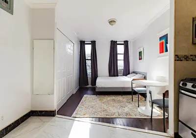a white room with a bed and a table at Spacious Upper East Side Studio, June To Aug 90 Days Stay Required in New York