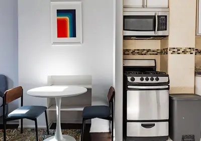 a kitchen with a stove and a microwave and a table at Spacious Upper East Side Studio, June To Aug 90 Days Stay Required in New York