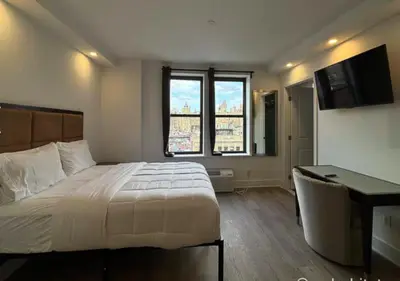 a bedroom with a large bed with a desk and two windows at Close to Times Square! Stunning Studio in NYC! in New York