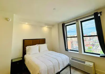 a bedroom with a bed and two windows at Close to Times Square! Stunning Studio in NYC! in New York