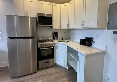 a kitchen with white cabinets and a stainless steel refrigerator at Close to Times Square! Stunning Studio in NYC! in New York