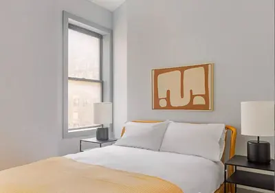 a white bedroom with a bed and two lamps at Midtown West 2 Bedroom Furnished Apartment Rental in New York