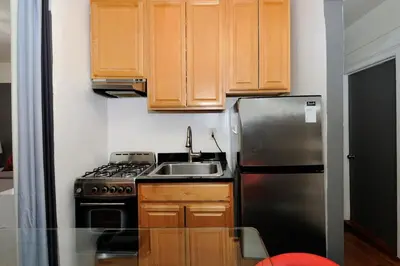 a kitchen with wooden cabinets and a stainless steel refrigerator at Furnished 2 Bedroom Apartment in Lennox Hill, June To Aug 90 Days Stay Required in New York