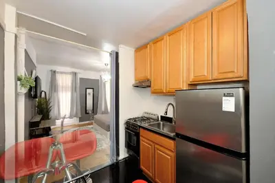 a kitchen with wooden cabinets and a stainless steel refrigerator at Furnished 2 Bedroom Apartment in Lennox Hill, June To Aug 90 Days Stay Required in New York