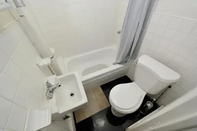 a bathroom with a toilet and a sink and a tub at Furnished 2 Bedroom Apartment in Lennox Hill, June To Aug 90 Days Stay Required in New York