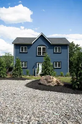 a blue house with a rock in front of it at Lakeview Villa with Private Hot Tub, Firepit & Breathtaking Cliff Views in Greenwood Lake
