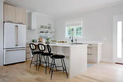 a kitchen with white cabinets and a white island with bar stools at Lakeview Villa with Private Hot Tub, Firepit & Breathtaking Cliff Views in Greenwood Lake