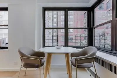 a table and chairs in a room with a window at Blueground Midtown E wd doorman nr E River NYC-1527 in New York