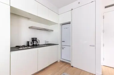a white kitchen with white cabinets and a refrigerator at Blueground Midtown S gym roof nr Times Sq NYC-1776 in New York
