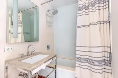 a bathroom with a sink and a shower curtain at Blueground Midtown S gym roof nr Times Sq NYC-1776 in New York