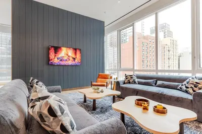 a living room with couches and a tv on a wall at Blueground LIC gym wd nr MoMA PS1 NYC-1796 in New York