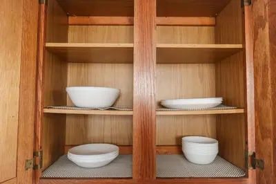 a cupboard with bowls and plates in it at Cozy 2BR 5min to NYC Train and 10min to Seton Hall in West Orange