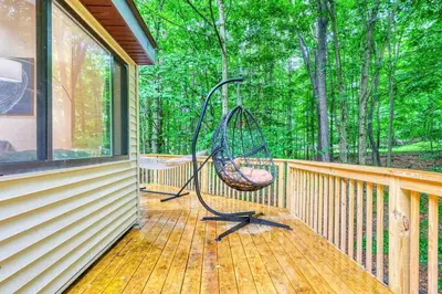 a swing on a porch of a house at Grand Woodland Retreat - Hot Tub - Game Room in Gouldsboro