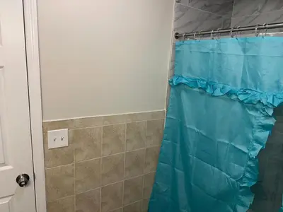 a shower with a blue shower curtain in a bathroom at Divine Villa and Resort - 32 Evergreen in Newark