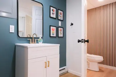 a bathroom with a sink and a mirror and a toilet at Scandinavian Retreat Hot Tub, Pool, Game Rm in Gouldsboro