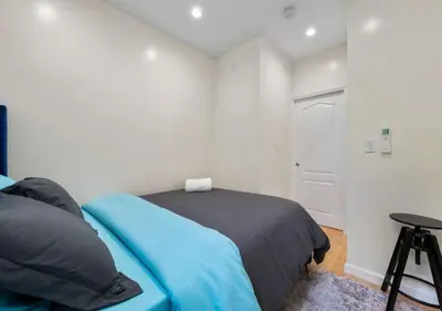 a bedroom with a blue bed and a stool at Amazing Location Murray Hill 3 Bedroom Apartment ,June to Aug 90 days stay required in New York