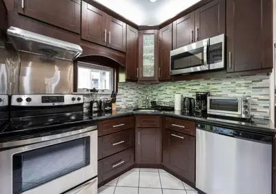 a large kitchen with wooden cabinets and appliances at Amazing Location Murray Hill 3 Bedroom Apartment ,June to Aug 90 days stay required in New York